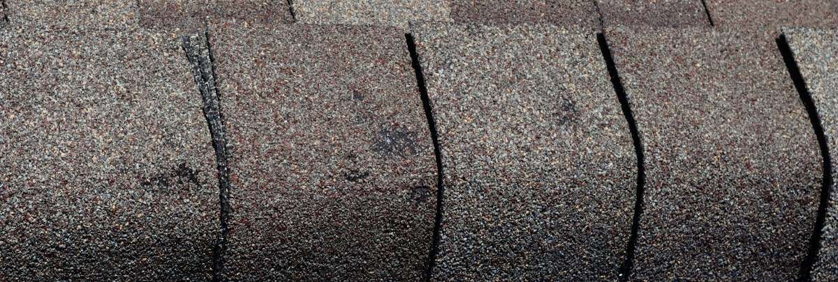 Close-up of granular loss on a shingle roof depicting damage and need for maintenance.